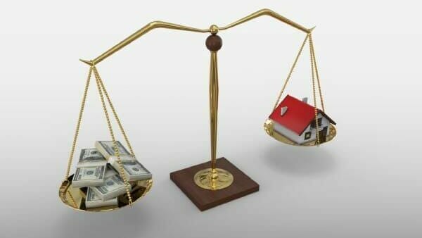 Money and a small house balancing on a scale, representing average mortgage payments in your state